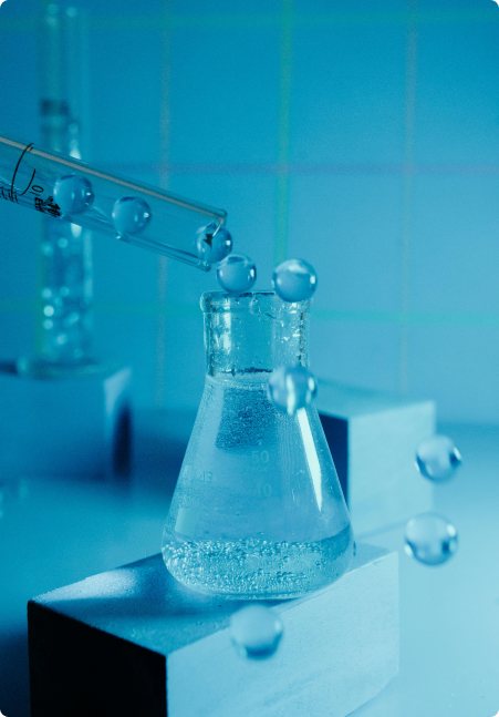 Laboratory flask with clear liquid being filled by a dropper, set against a blue background