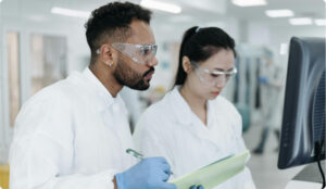Two lab technicians studying a computer screen
